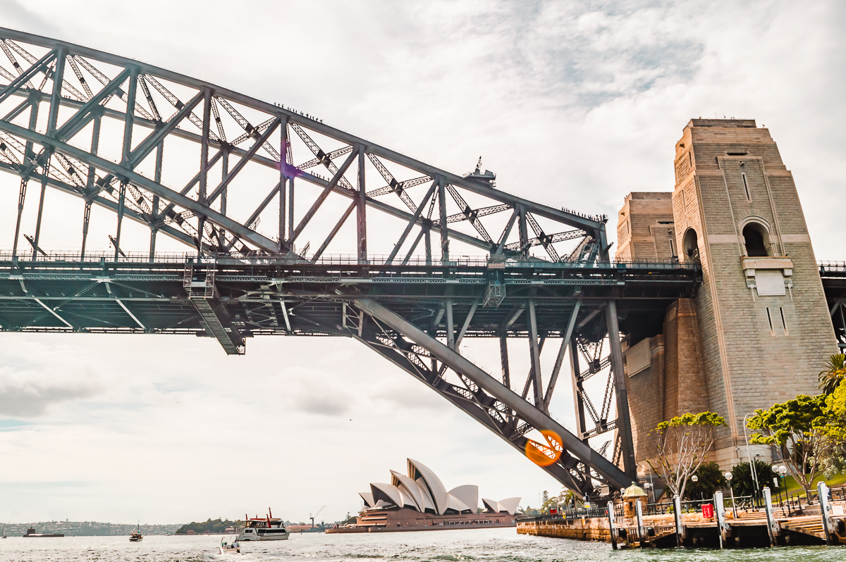 The Sydney Opera House peeking out underneath the Sydney Harbour Bridge.
