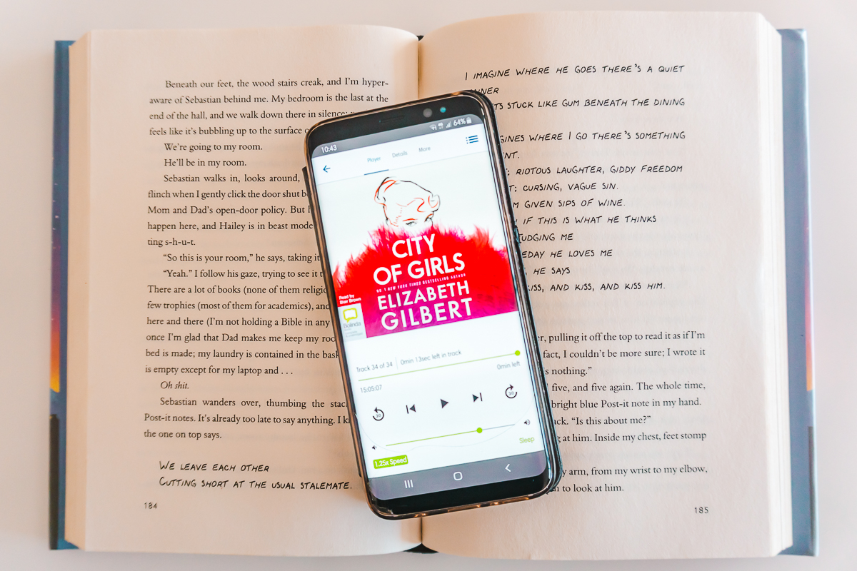 Audiobook of City of Girls displayed on phone and sitting in an opened book.